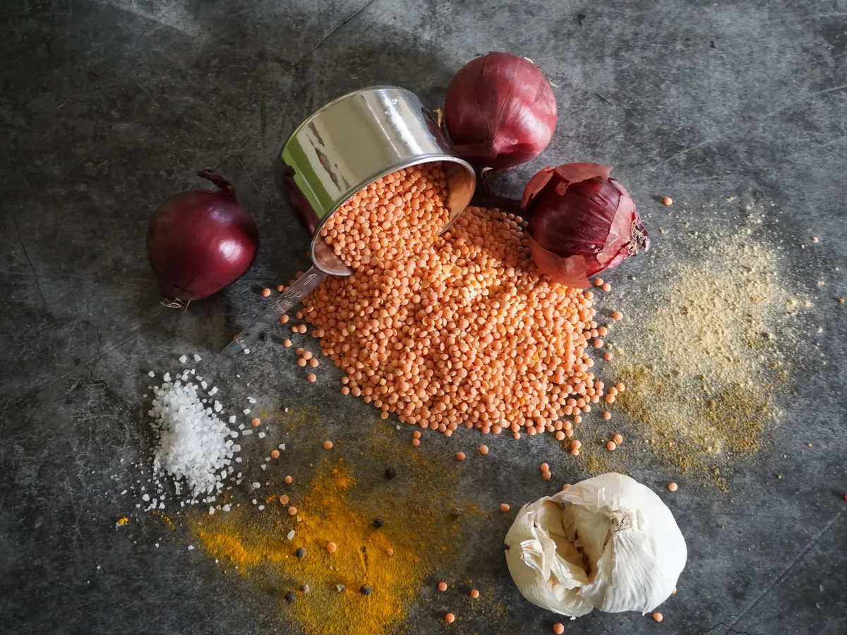 Rote Linsen, Zwiebeln, Knoblauch und Gewürze auf einer Steinplatte